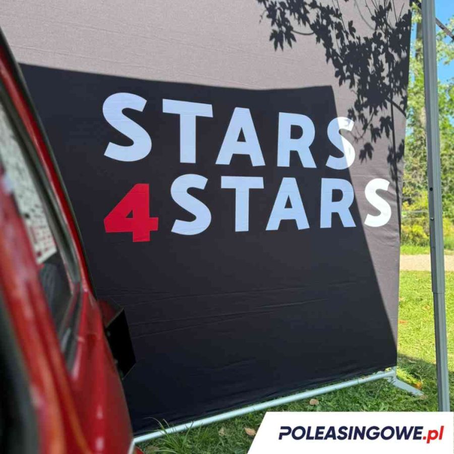 Logo Stars 4 Stars na czarnym tle baneru podczas wydarzenia plenerowego. Na pierwszym planie fragment czerwonego pojazdu, symbolizującego udział w inicjatywie wspieranej przez Poleasingowe.pl