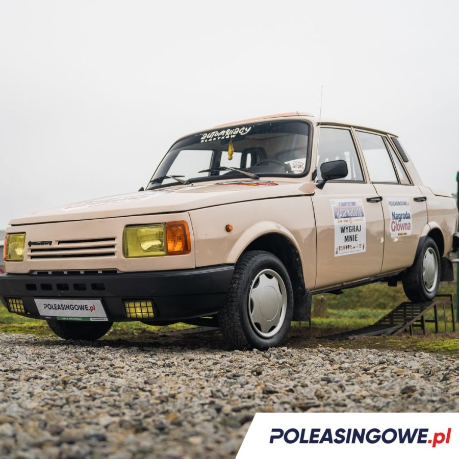 Cały Wartburg z bocznymi naklejkami informującymi o nagrodzie głównej i wydarzeniu, w tle widoczne jest niebo oraz otoczenie przygotowane na aukcję.